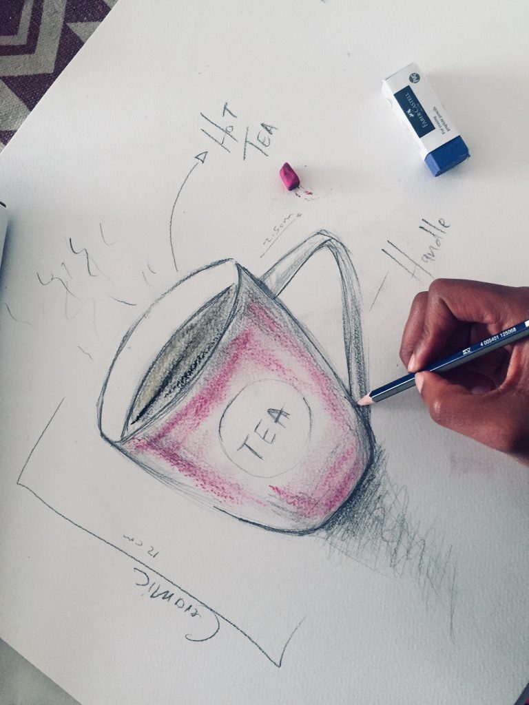 Hand sketching a tea cup design with pencil